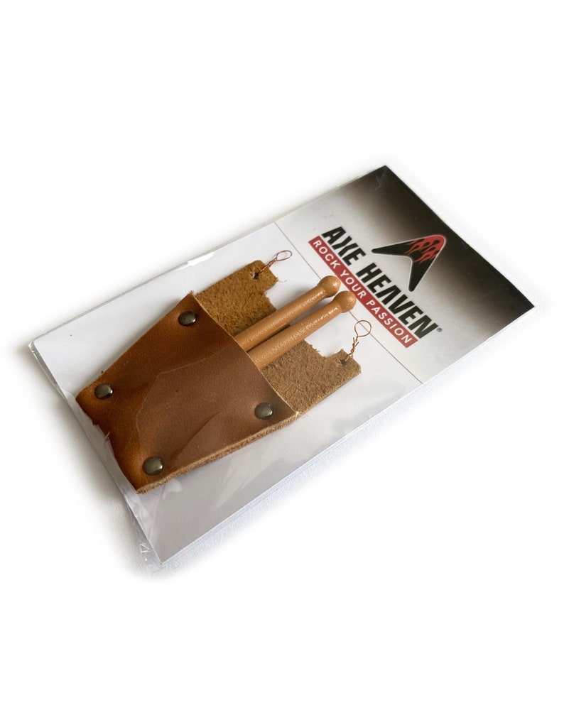 Puede incluir: Un porta baquetas de cuero marr&oacute;n con dos baquetas de madera en su interior. El porta baquetas tiene una solapa que se cierra con un broche a presi&oacute;n. El embalaje tiene el texto "Axe Heaven Rock Your Passion".