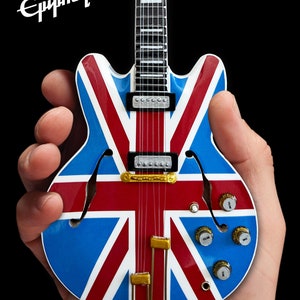 May include: A miniature Epiphone guitar with a Union Jack design. The guitar is blue, red, and white with gold hardware.