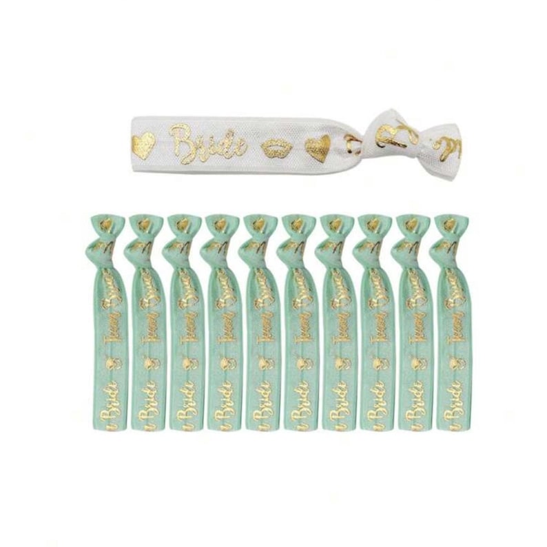 May include: Set of 11 green and gold elastic hair ties with the word "Bride" printed on them. One hair tie is white with gold glitter and the words "Bride" and a heart, lips, and heart design.