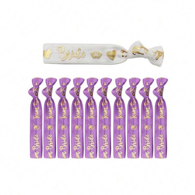 May include: Purple and white elastic hair ties with gold lettering. The purple hair ties say "Team Bride" and the white hair tie says "Bride".