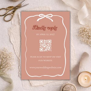 Puede incluir: Invitación de boda de color rosa pálido con borde blanco y diseño de lazo. Se muestra el texto "Kindly reply", junto con la fecha 12 de abril de 2027 y un código QR. La invitación también incluye una dirección web.