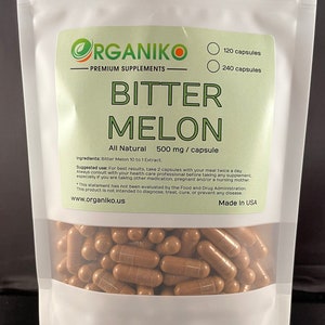 May include: A white pouch of "Bitter Melon" capsules from Organiko. The label is green and white, with text indicating "All Natural" and 500 mg per capsule. The pouch contains brown capsules, with options for 120 or 240 capsules.