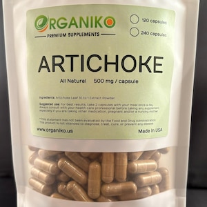 Op de afbeelding: Een witte hersluitbare zak met een groen label waarop "ORGANIKO - PREMIUM SUPPLEMENTS" en "ARTICHOKE All Natural 500 mg/capsule" staat. Het label bevat ook de ingrediënten, het aanbevolen gebruik en een disclaimer. De zak bevat een grote hoeveelheid bruine capsules.