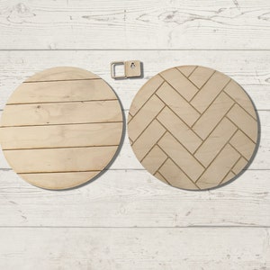 May include: Two unfinished, round wooden wall decor pieces. One has horizontal plank detailing, the other a herringbone pattern. A small wooden hanging bracket is also included. The wood is a light, natural color.