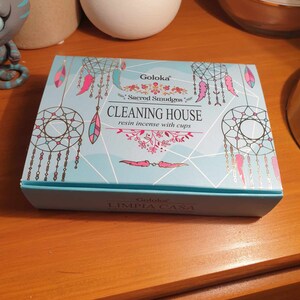 May include: A blue box with a dreamcatcher design and the text "Goloka Sacred Smudges Cleaning House resin incense with cups" and "Goloka LIMPIA CASA".
