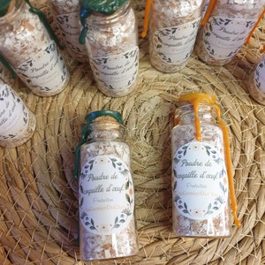 Peut inclure: Une collection de petites bouteilles en verre remplies de poudre blanche et scellées avec des bouchons en liège. Les bouteilles portent des étiquettes qui indiquent "Poudre de coquille d'œuf", ce qui se traduit par "Poudre de coquille d'œuf". Les étiquettes comprennent également le texte "Protection" et "Au Grenier Du Chat".