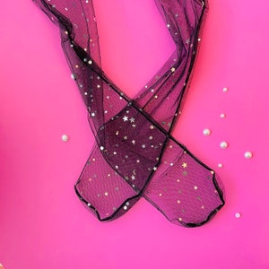 Puede incluir: Medias negras transparentes con estrellas doradas brillantes sobre un fondo rosa.