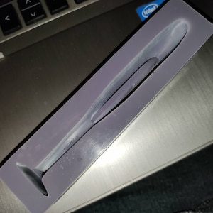 May include: A purple silicone mold for making a long, thin, tapered object with a rounded tip.