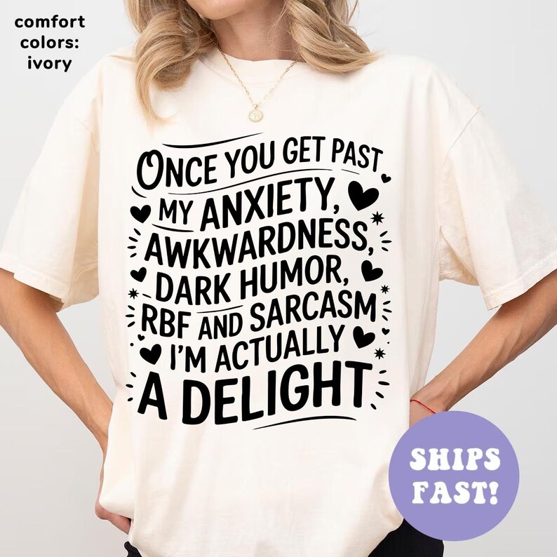 May include: A white t-shirt with black text that reads "Once you get past my anxiety, awkwardness, dark humor, RBF and sarcasm I'm actually a delight".