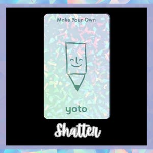 Op de afbeelding: Een witte kaart met een holografische achtergrond waarop een groene potlood met een glimlachend gezicht is afgebeeld. De kaart heeft de tekst "Make Your Own" en "yoto" erop gedrukt. De tekst "Shatter" is in zwart onder de kaart gedrukt.
