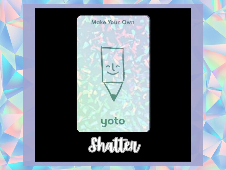 Op de afbeelding: Een witte kaart met een holografische achtergrond waarop een groene potlood met een glimlachend gezicht is afgebeeld. De kaart heeft de tekst "Make Your Own" en "yoto" erop gedrukt. De tekst "Shatter" is in zwart onder de kaart gedrukt.