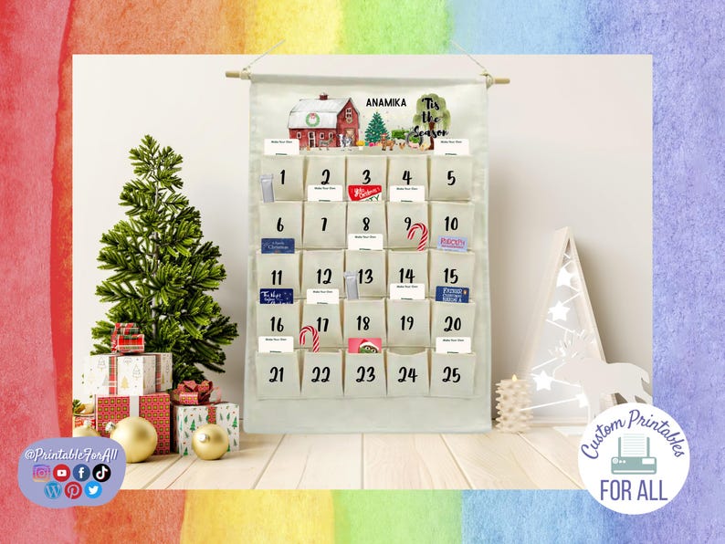 Op de afbeelding: Een witte canvas adventskalender met 25 genummerde vakjes. De kalender heeft een aquarel illustratie van een huis met een kerstboom en de tekst "Tis the Season". De naam "Anamika" staat bovenaan de kalender gedrukt.
