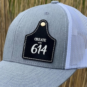 May include: Gray and white trucker hat with a black leather patch that says "CREATE with 614".