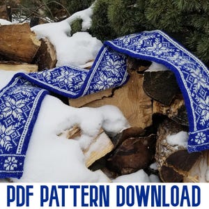 May include: A blue and white knitted scarf with a snowflake pattern, resting on a pile of wood and snow. The text "PDF PATTERN DOWNLOAD" is at the bottom of the image.