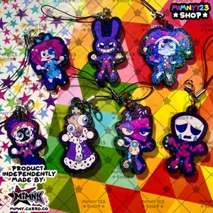 Puede incluir: Una colección de coloridos y brillantes colgantes de personajes con cordones negros. Los colgantes presentan varias figuras de dibujos animados en tonos morados, azules y rosas. El texto "MIMNY123 SHOP" es visible en el fondo.