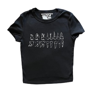 May include: A black short-sleeve t-shirt featuring a white graphic print of various human teeth arranged in two rows across the chest. The inner neck label displays the text DECAYEDCEREBRUM in white lettering on a black background.