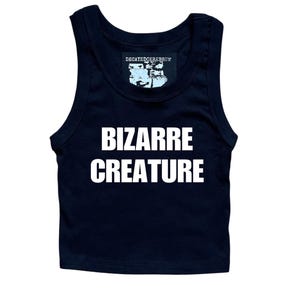 May include: A black sleeveless crop top featuring the white text BIZARRE CREATURE printed on the front. The garment includes a black inner neck label with the white text DECAYEDCEREBRUM and a graphic illustration of a skull above the brand name.