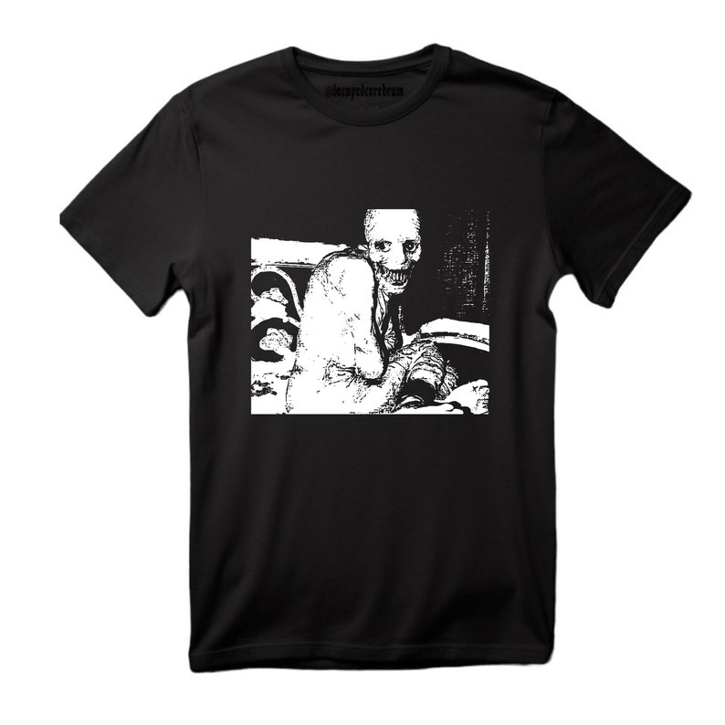 May include: Black t-shirt with a white graphic print of a creepy, distorted human figure with a wide smile.