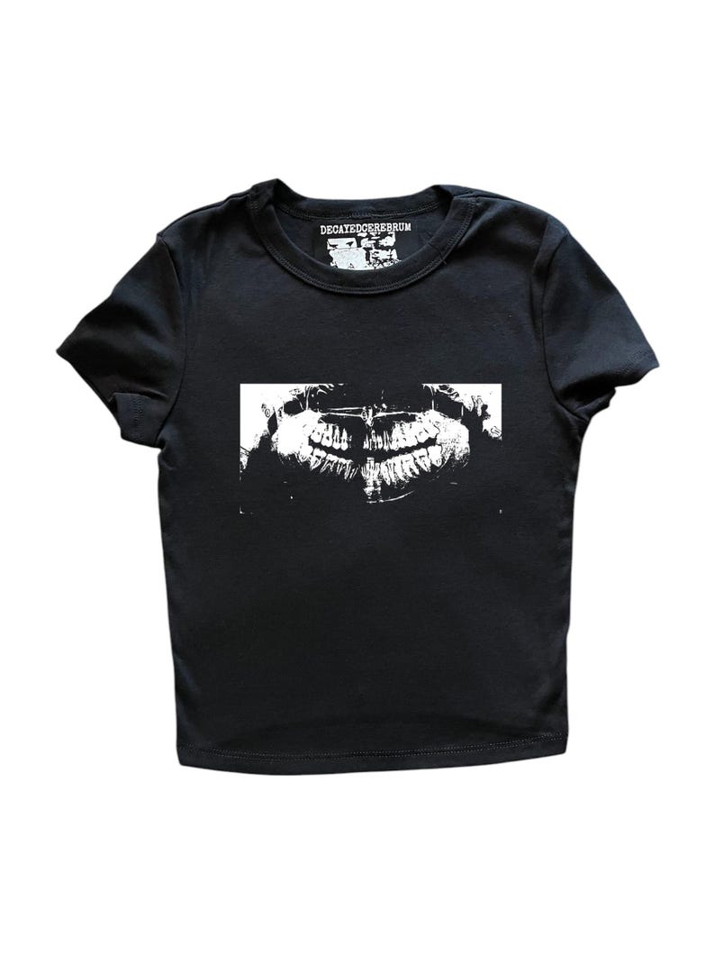 May include: Black t-shirt with a white graphic of a dental X-ray. The shirt has a crew neck and short sleeves. The text "DECAYEDCEREBRUM" is printed above the graphic in white.