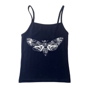 May include: Navy blue camisole top with thin straps. The top features a large white graphic of a moth with detailed wing patterns. The text "@deanydoodlesartrus" is printed at the bottom of the top.