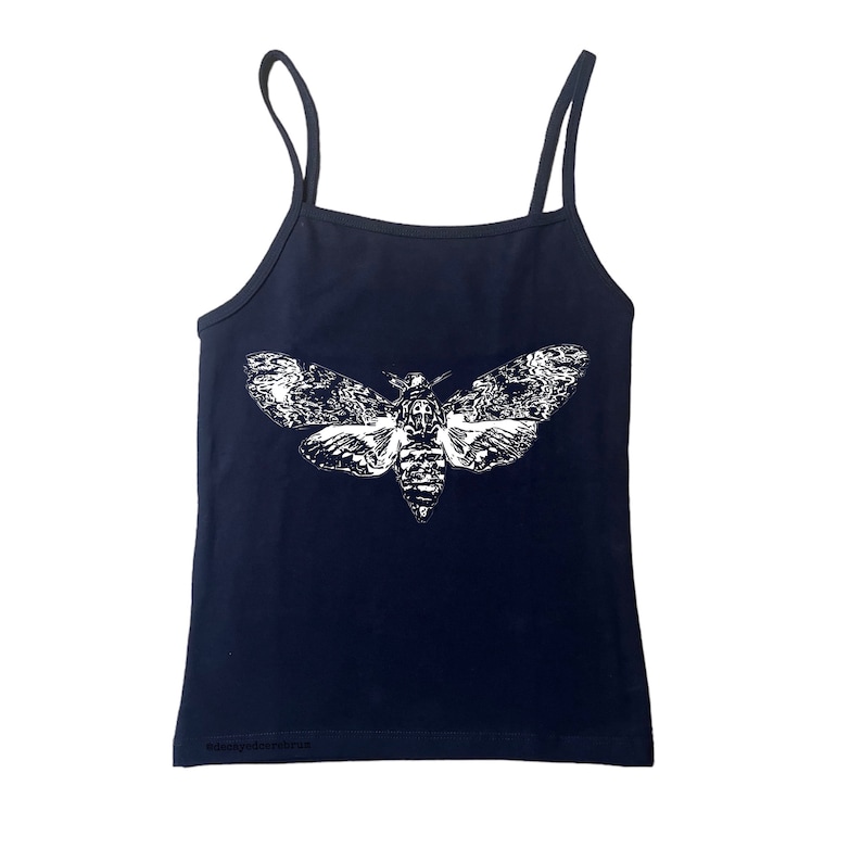 May include: Navy blue camisole top with thin straps. The top features a large white graphic of a moth with detailed wing patterns. The text "@deanydoodlesartrus" is printed at the bottom of the top.