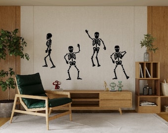May include: Five black skeleton figures are displayed on a white wall. The skeletons are in various poses, including dancing and playing music. The wall is decorated with a wooden shelf and a green plant.
