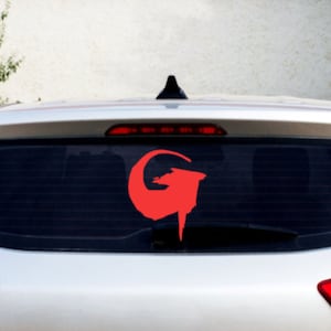 May include: A silver car with a red G logo sticker on the rear window.