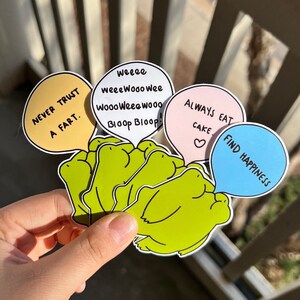 May include: Five frog stickers with speech bubbles. The speech bubbles say "Never trust a fart", "weeee weeeWooo Wee Wooo Weeewoooo Bloop Bloop", "Always eat cake", and "Find happiness".