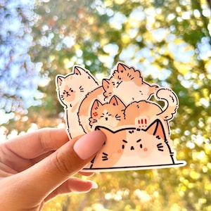 May include: A sticker featuring a stack of four cartoon cats. The cats are all orange and white with black eyes and noses. The bottom cat is looking directly at the viewer with a grumpy expression. The other cats are stacked on top of each other, with the top cat looking off to the side. The sticker is on a clear background.