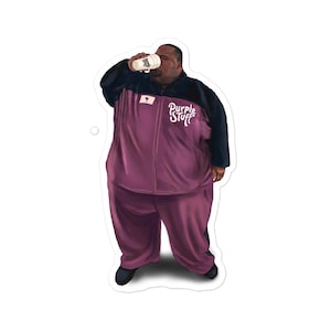 Peut inclure: Un homme portant un survêtement violet et noir avec les mots "Purple Stuff" sur la poitrine. Il tient une tasse blanche et boit dedans.
