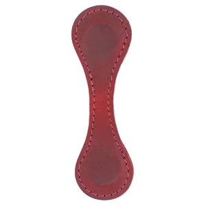 Puede incluir: Un marcap&aacute;ginas de cuero rojo con cierre magn&eacute;tico. El marcap&aacute;ginas est&aacute; cosido con hilo rojo.