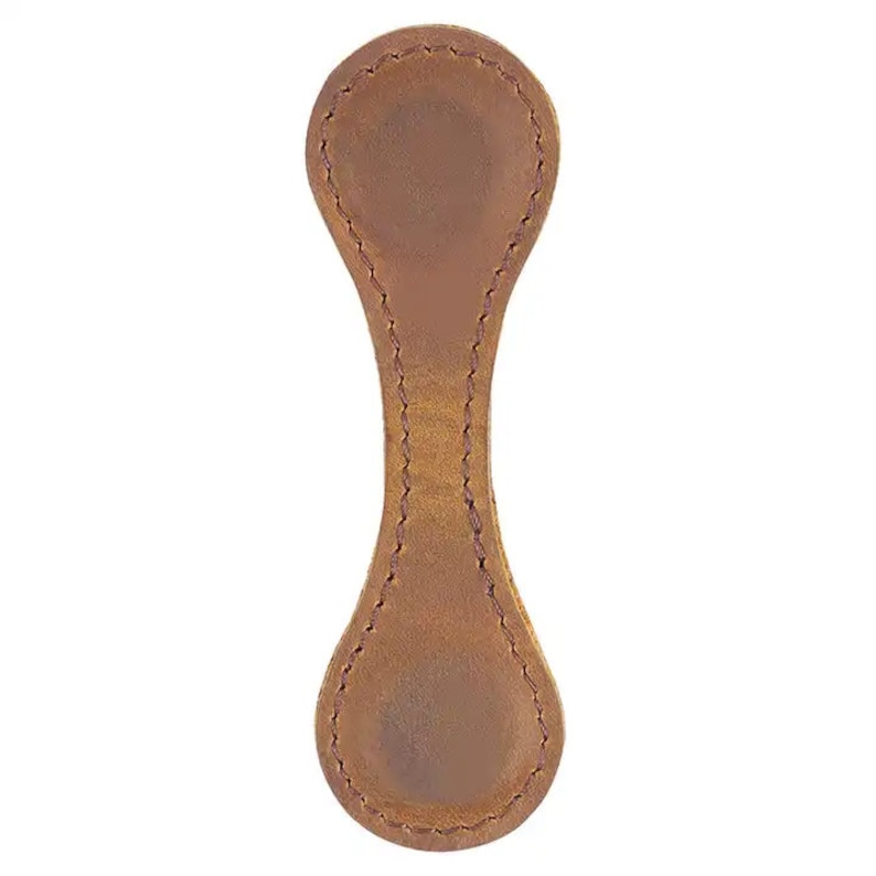 Puede incluir: Un marcap&aacute;ginas de cuero marr&oacute;n con un borde cosido y una forma redondeada.