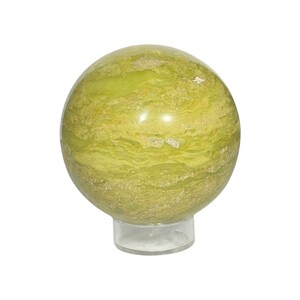 May include: A spherical, polished gemstone in shades of green and yellow, displayed on a clear plastic stand. The stone features a swirling, banded pattern and a glossy finish, suitable as a decorative item or collectible.
