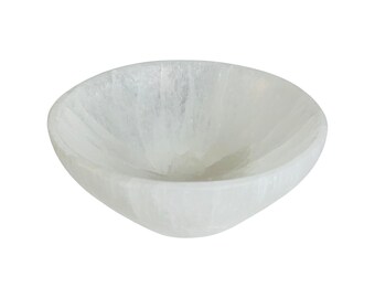 Puede incluir: Un cuenco de selenita blanco con una superficie lisa y pulida. El cuenco está hecho de cristal de selenita natural y tiene una forma única y orgánica.