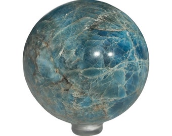 Puede incluir: Una esfera de piedra preciosa azul y verde con una base de vidrio transparente. La esfera tiene un aspecto marmoleado.
