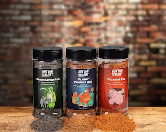 May include: Three glass jars of barbecue rub with labels that say "How Low Go Slow?" and have different names and illustrations. The labels are "Grim Reaper Rub", "Flabby Phoenix Rub", and "Pigasus Rub".