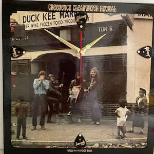 May include: A vintage vinyl record album cover featuring a band of five men standing in front of a brick building. The album cover is for Creedence Clearwater Revival's album "Willy and the Poor Boys".