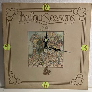 May include: A vintage record album cover featuring a clock face with Roman numerals and a picture of four musicians in period clothing. The album title is "The Four Seasons Story".