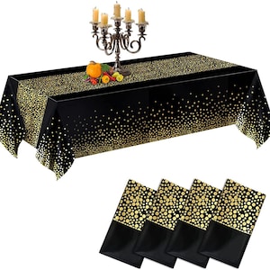 May include: Black and gold confetti table cover with four matching napkins. The table cover has a black background with gold confetti scattered across it. The napkins are black with gold confetti.