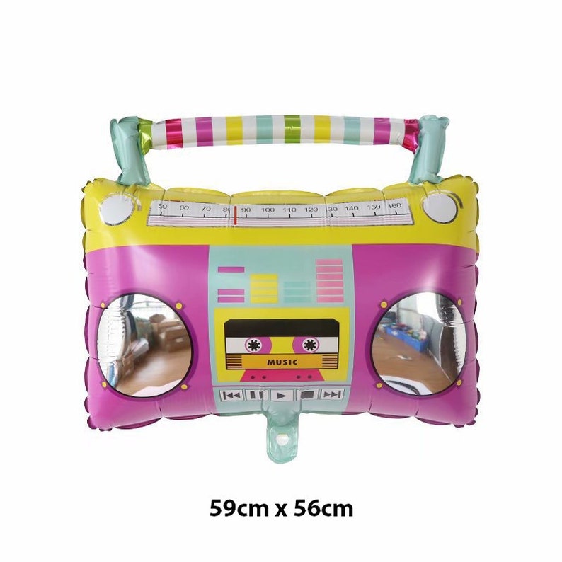 May include: A pink and yellow inflatable boombox balloon with a rainbow handle. The balloon has a cassette tape with the word "MUSIC" on it. The balloon is 59 inches by 56 inches.