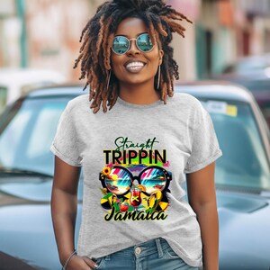 May include: A light gray t-shirt with the words "Straight Trippin' Jamaica" printed on the front. The graphic includes sunglasses with a beach scene, a sunflower, and tropical drinks. The shirt is short-sleeved.