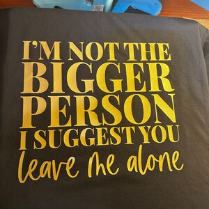 May include: Black t-shirt with gold lettering that reads "I'm not the bigger person I suggest you leave me alone."