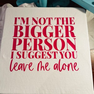 May include: A white t-shirt with the text "I'm not the bigger person I suggest you leave me alone" printed in pink.