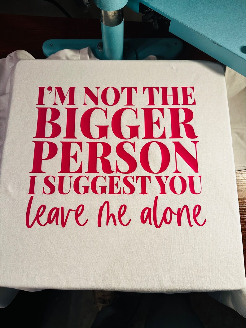May include: A white t-shirt with the text "I'm not the bigger person I suggest you leave me alone" printed in pink.