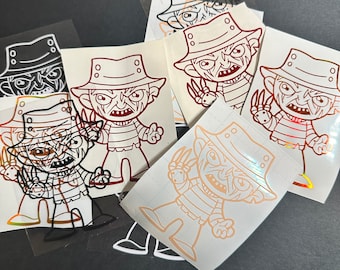 May include: A set of five Freddy Krueger vinyl decals in various colors, including black, white, red, and brown. The decals feature a cartoon-style Freddy Krueger with a striped shirt and a hat.