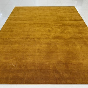 Puede incluir: Una alfombra de color amarillo mostaza sólido con una textura suave y mullida.