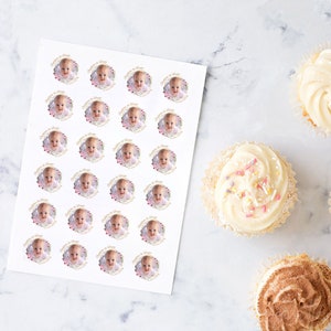 May include: A sheet of white sticker paper with 36 round stickers featuring a baby's photo in a gold frame with pink and gold hearts. The stickers are perfect for decorating cupcakes or other treats.