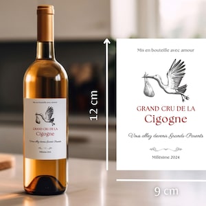 May include: A white wine bottle with a label that says "Grand Cru de la Cigogne" and "Vous allez devenir Grands-Parents" with a stork illustration. The bottle is 12 inches tall and the label is 9 inches wide.