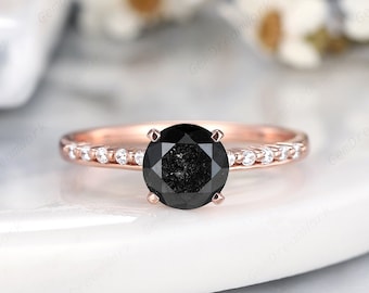 May include: A rose gold engagement ring with a black diamond center stone and a band of smaller diamonds.