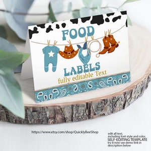 May include: Printable food labels for a baby shower with a cowboy theme. The labels feature a blue baby onesie, a cowboy hat, a bandana, and cowboy boots hanging on a clothesline. The text "FOOD LABELS fully editable Text" is printed on the labels.